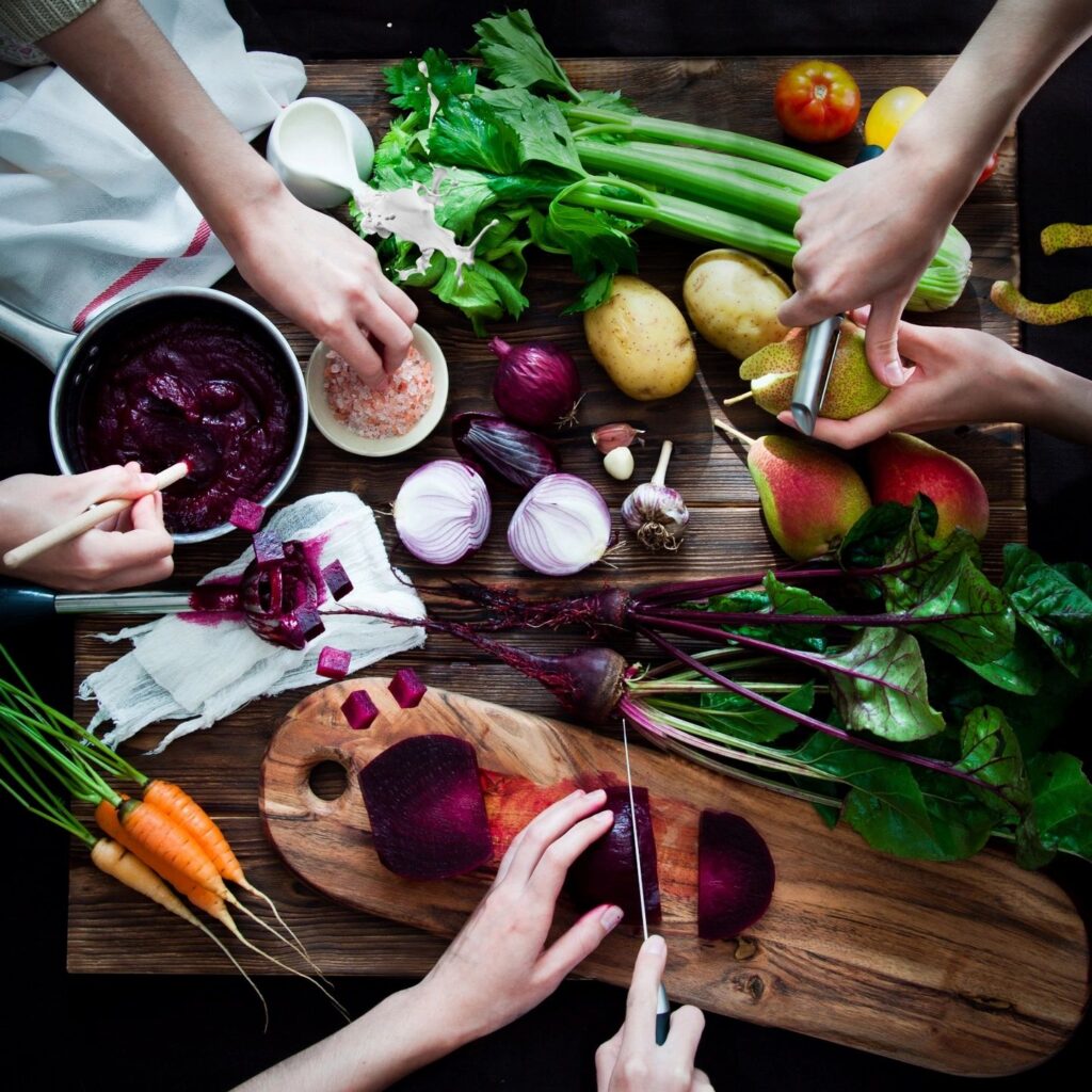 hands preparing pears, beets, and other produce