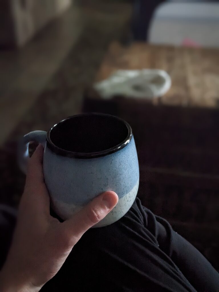 hand holding a mug, resting on a knee